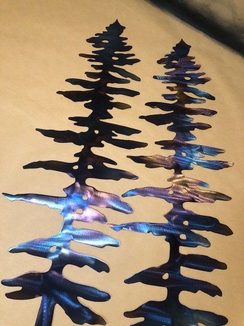 Black metal tree silhouettes with blue-purple lights on a warm beige background.