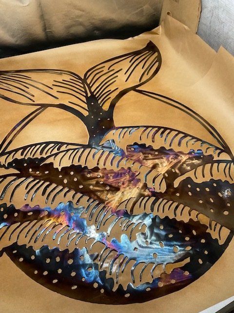 Colorful glittery whale-tail painting on a cardboard cutout, with blue, purple, and gold accents