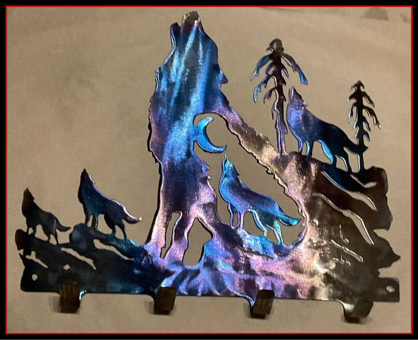 Silhouette of wolves around a glowing blue-purple pine tree scene on a metal wall art piece