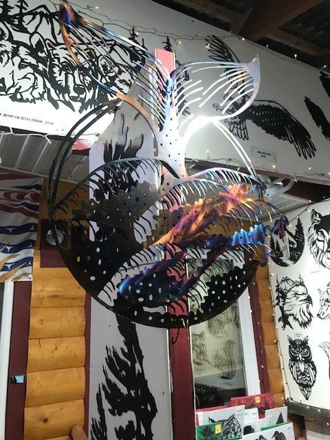 Black reflective hanging sculpture with leaf-like cutouts in an indoor space