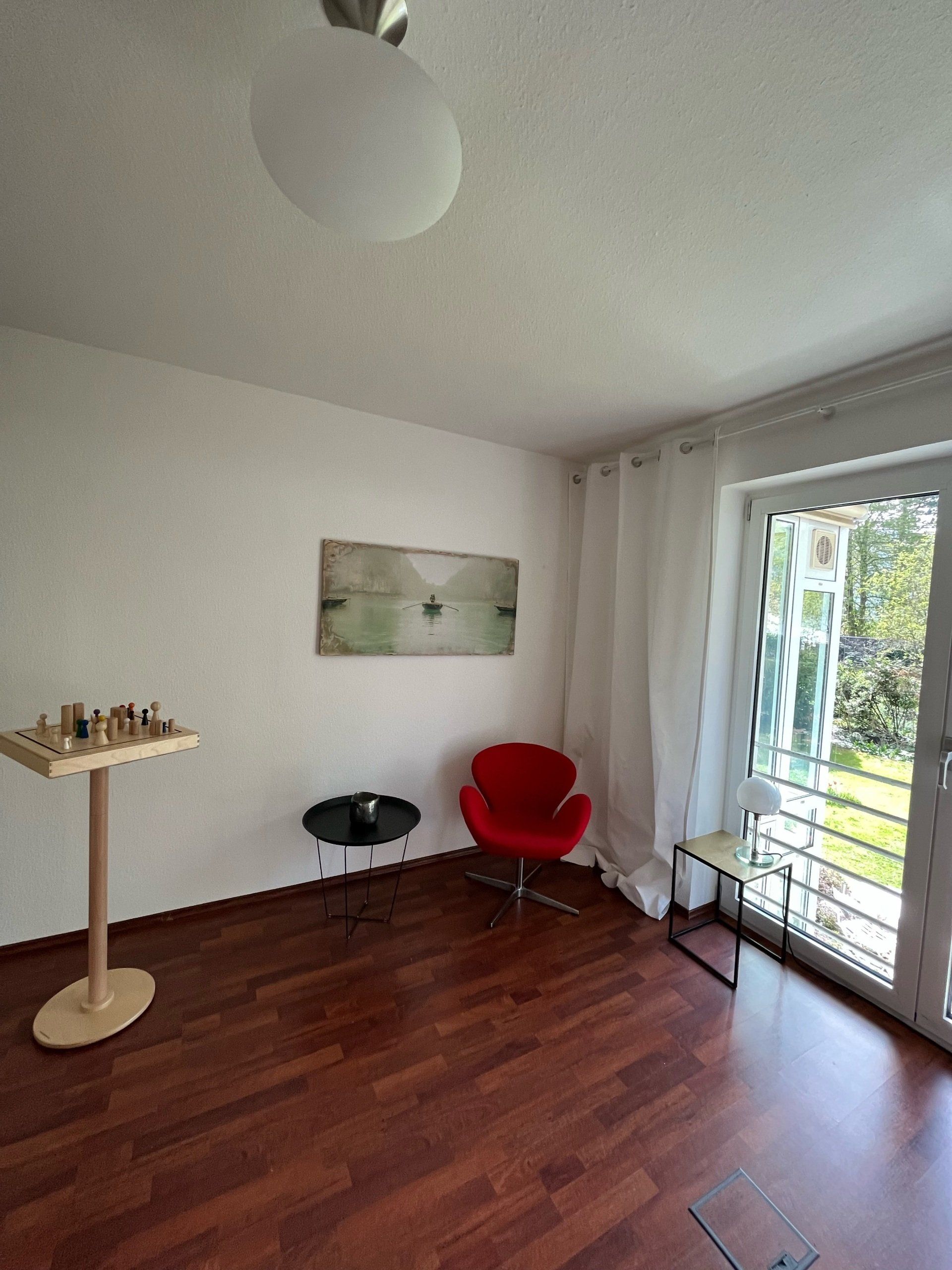 Ein Wohnzimmer mit einem roten Stuhl und einem Tisch mit einem Schachbrett darauf