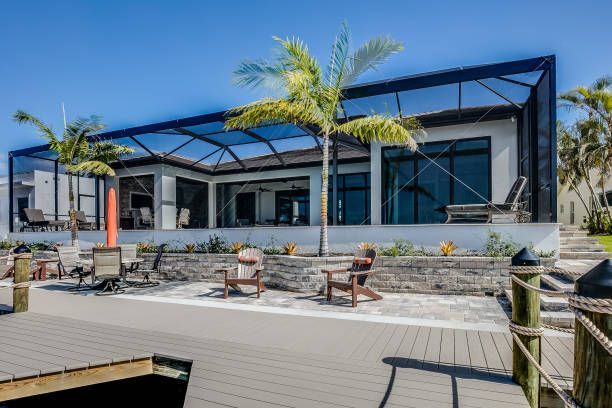 A large house with a screened in porch and a dock in front of it.
