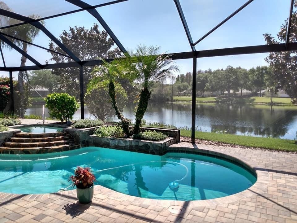 A screened in swimming pool with a view of a lake