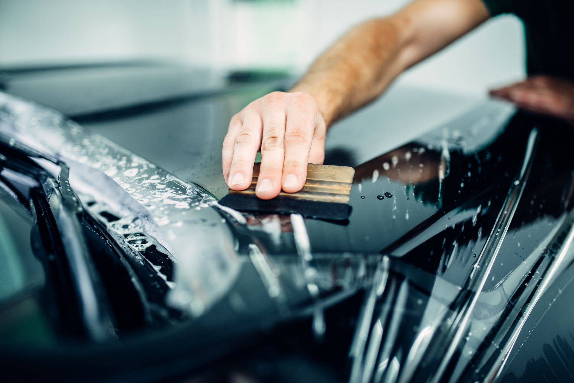 A person using a tool to apply tint to a car window.
