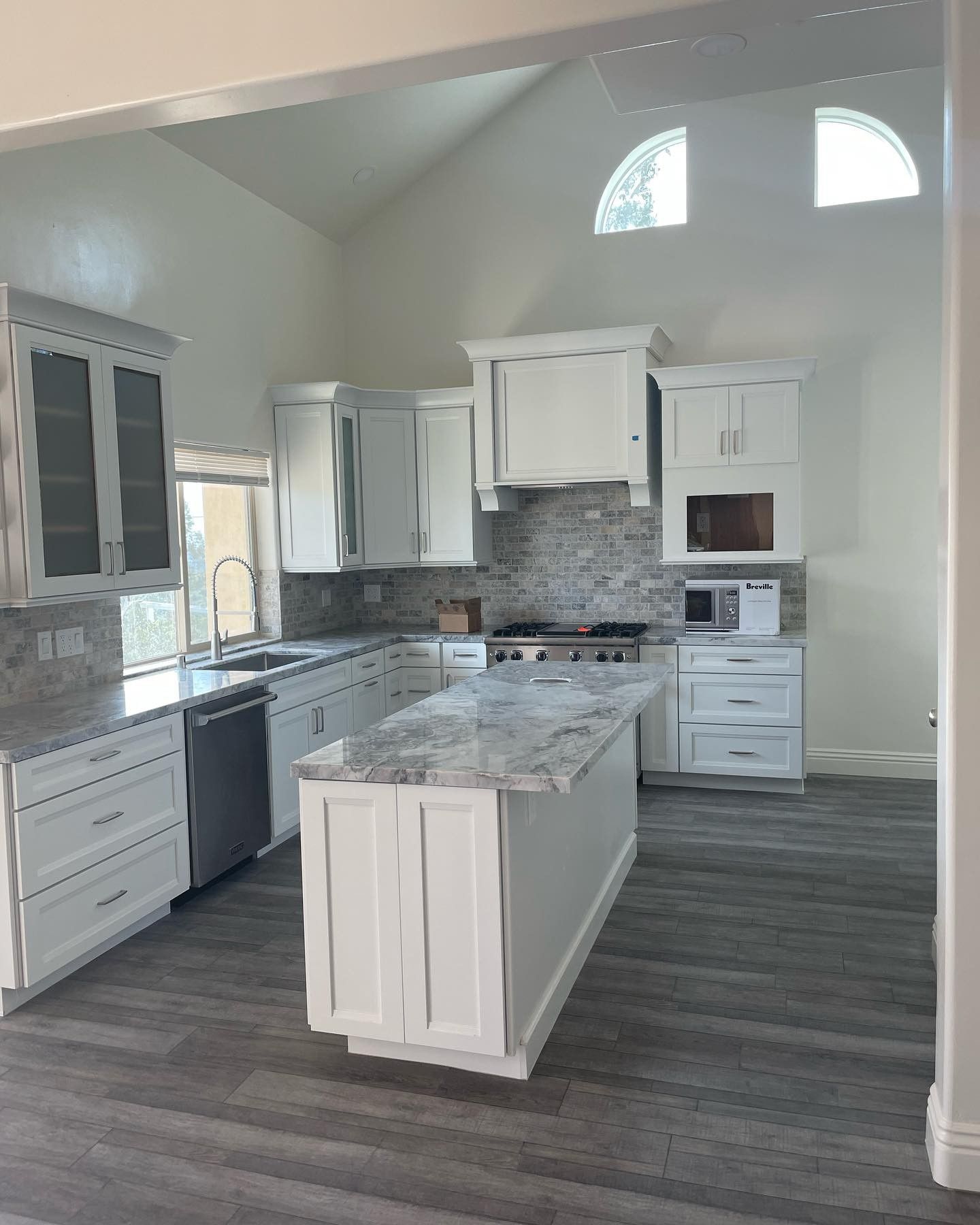 A kitchen with white cabinets and a large island in the middle.