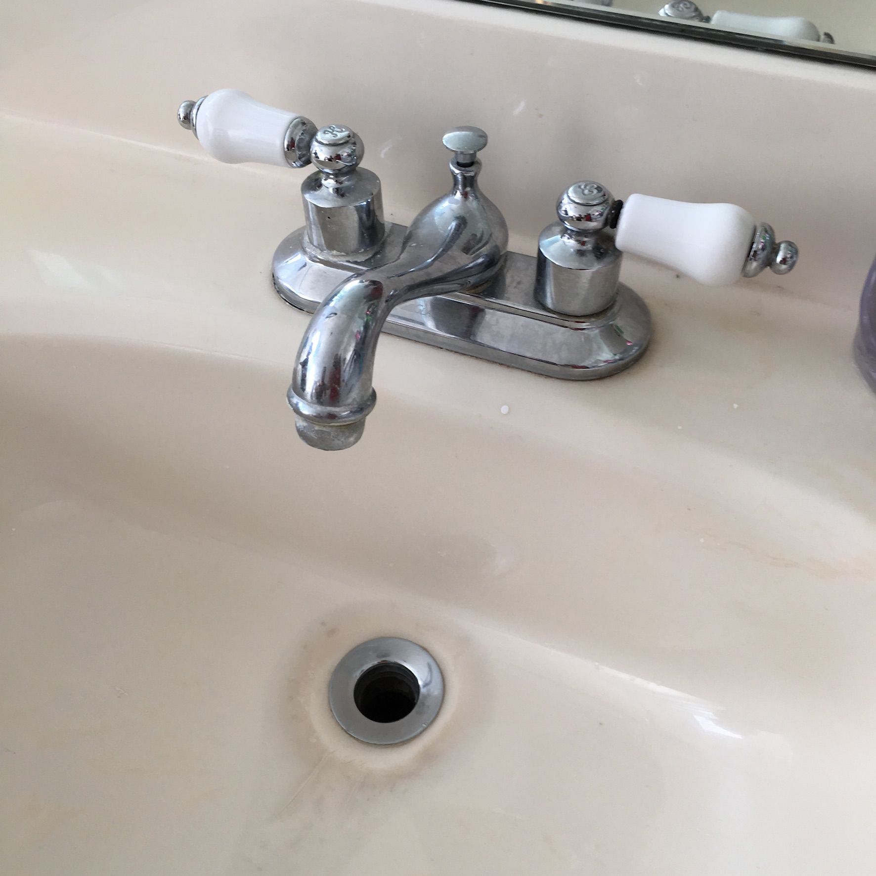 A bathroom sink with a chrome faucet and white handles