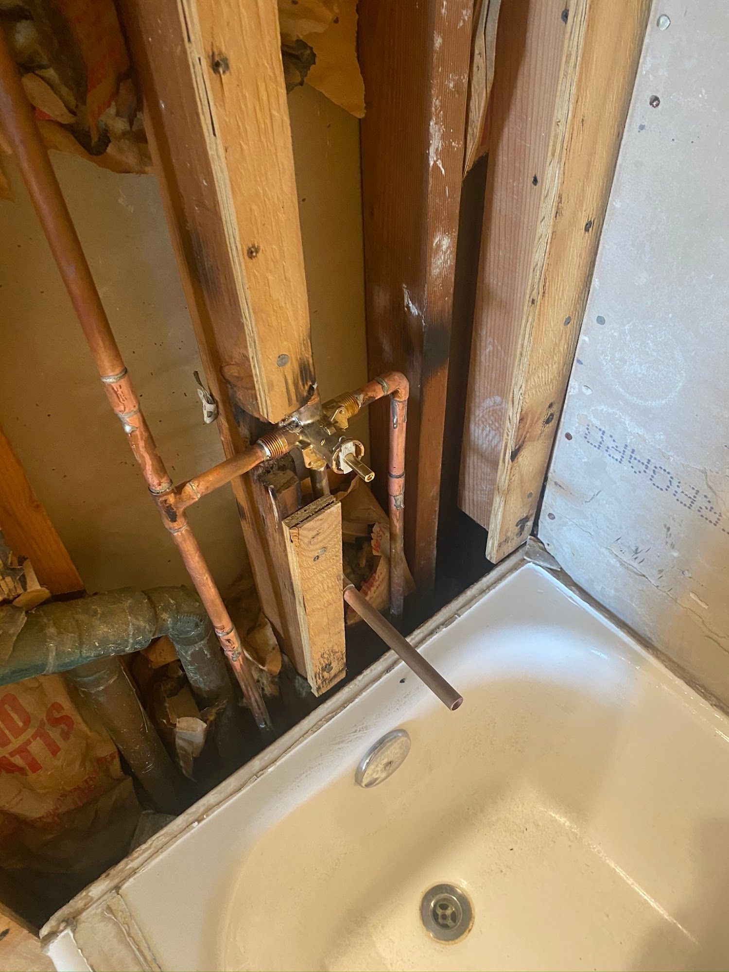 A bathtub is under construction in a bathroom with pipes coming out of the wall.