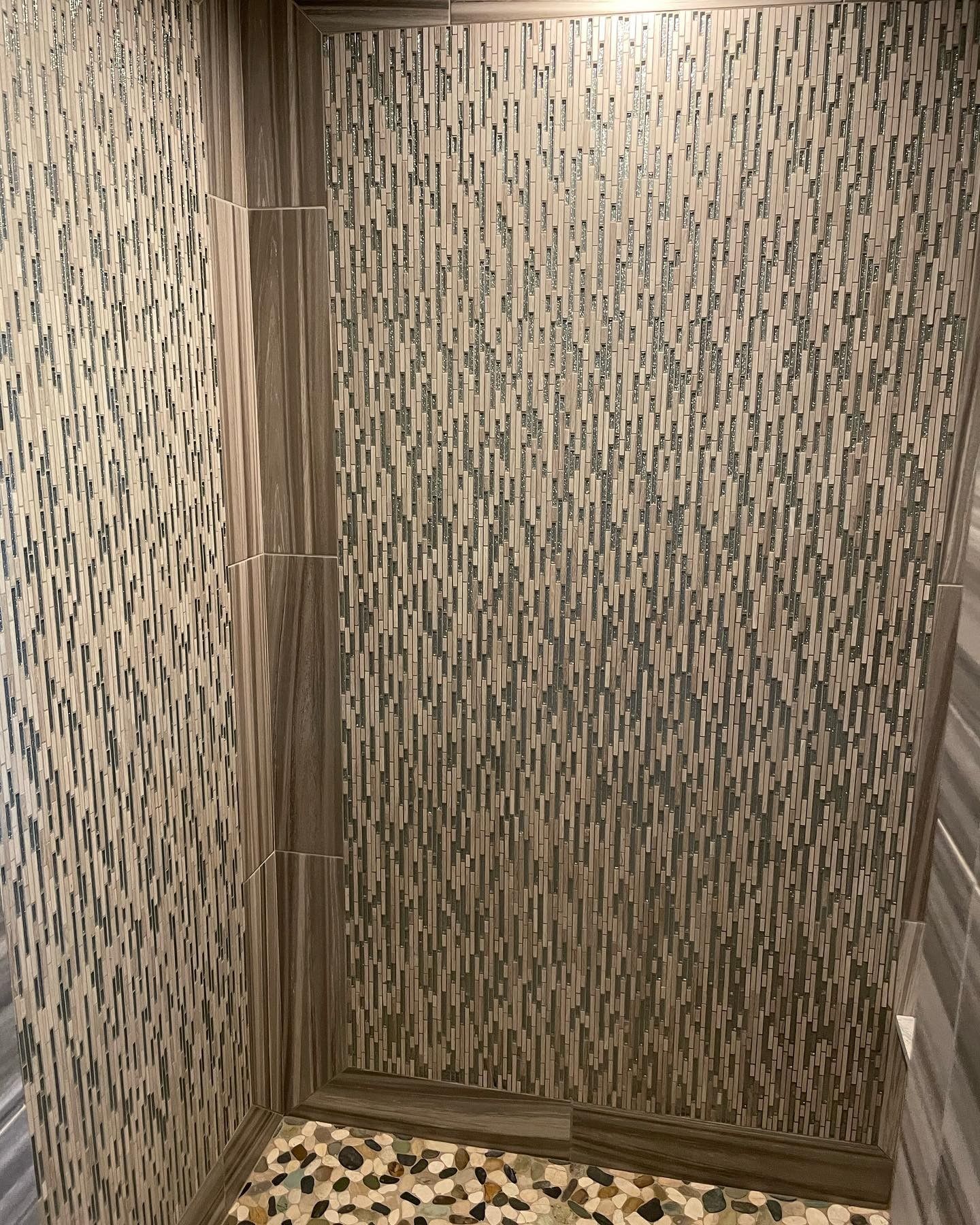 A bathroom with a walk in shower and a tiled wall.