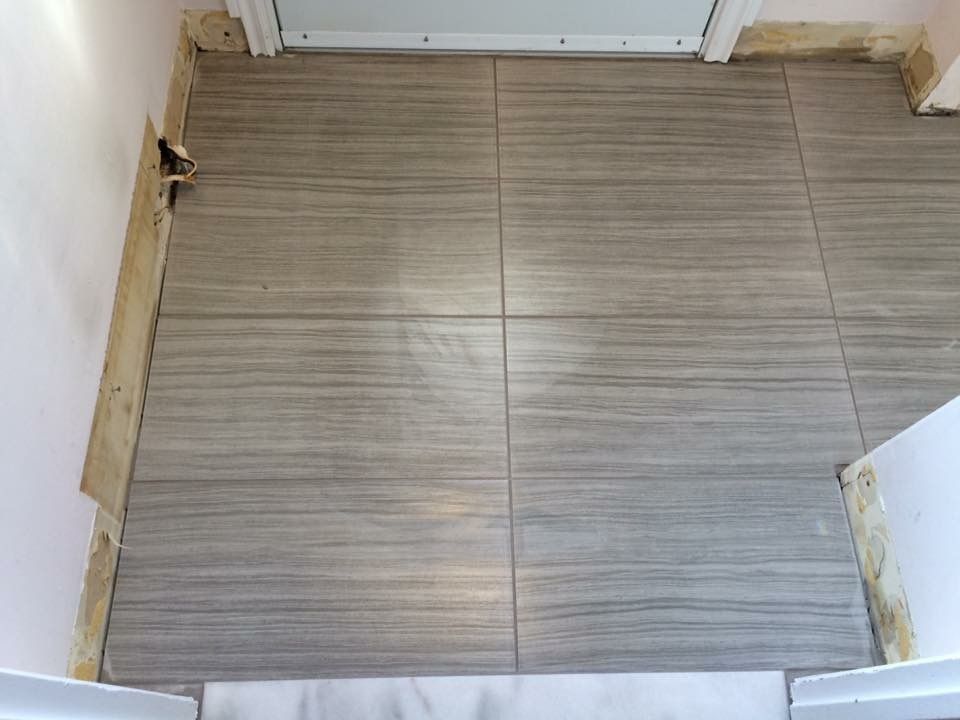A tiled floor is being installed in a room next to a door.