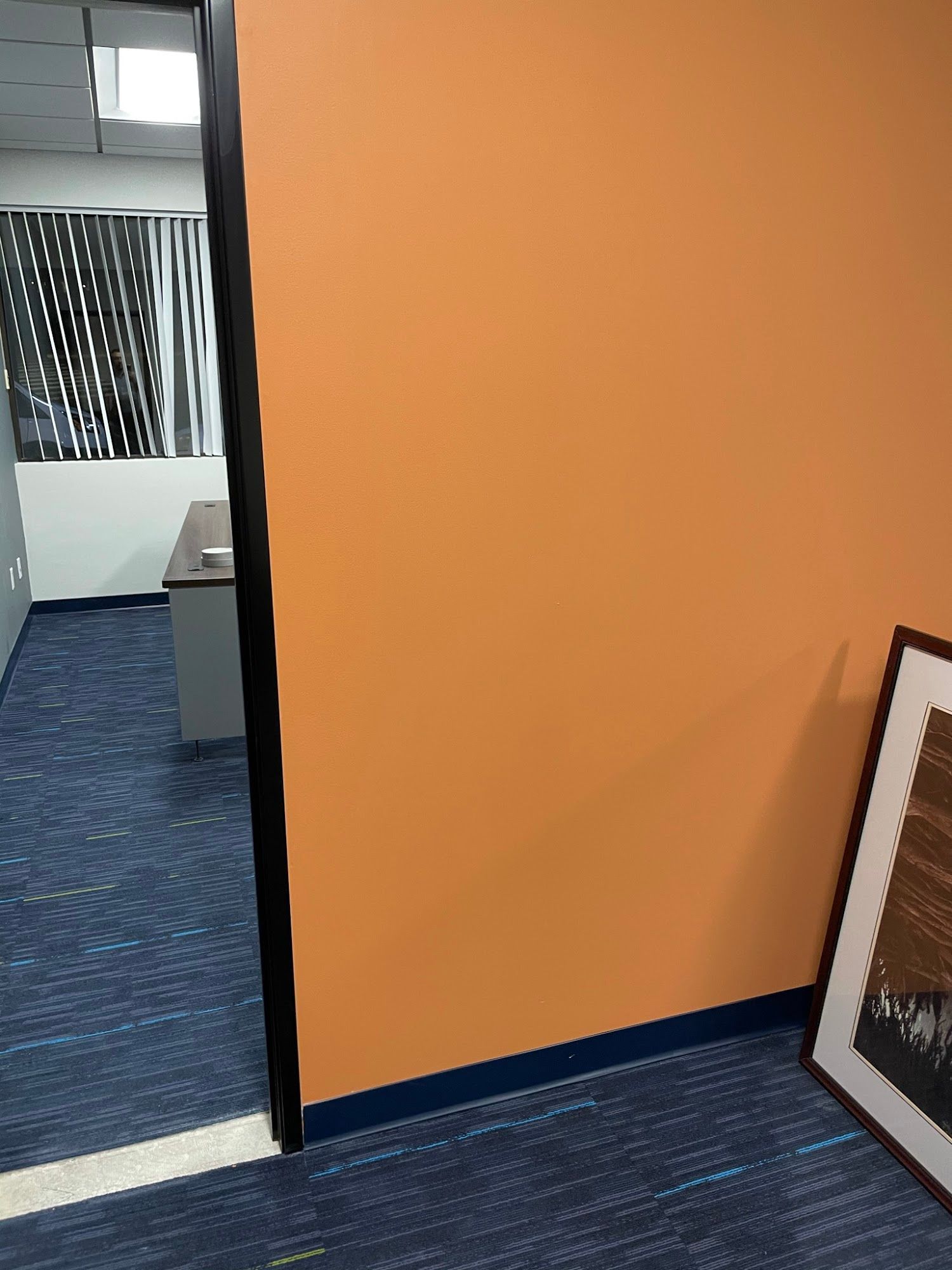 A room with an orange wall and a picture on the floor.