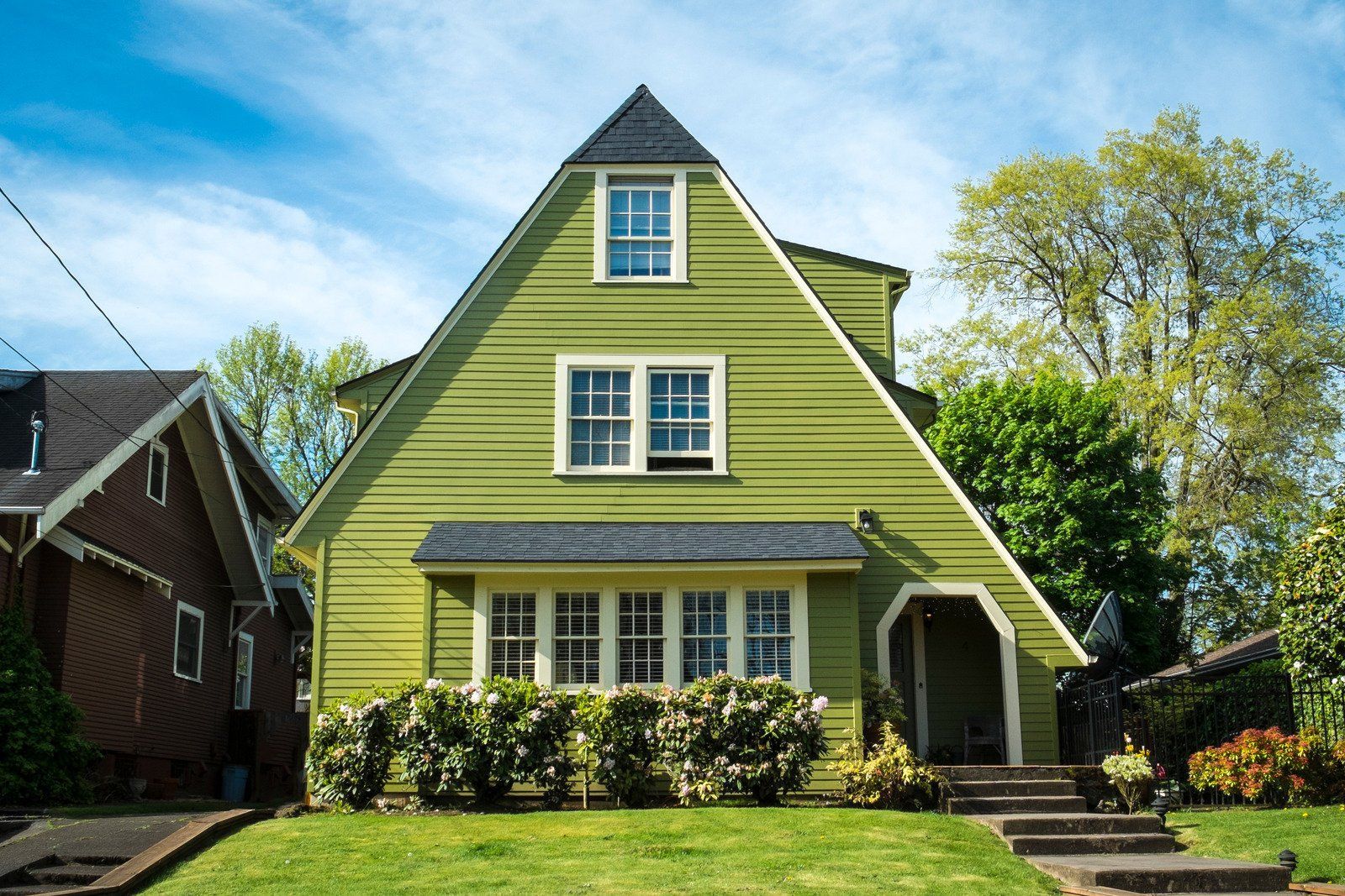A green house with a pyramid shaped roof is sitting on top of a lush green lawn.