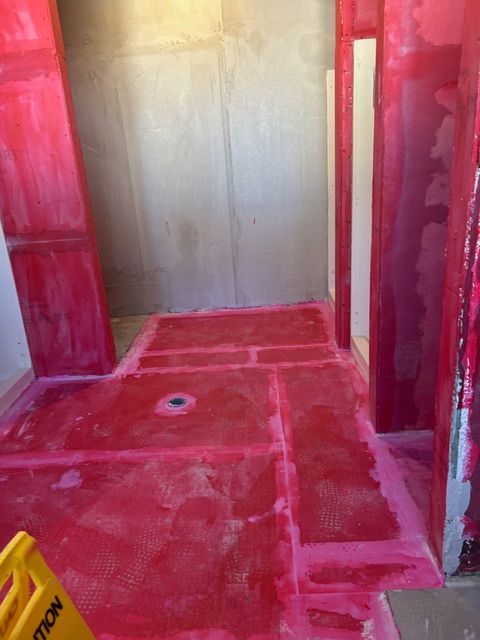 Red waterproof membrane installed in a shower before tiling.