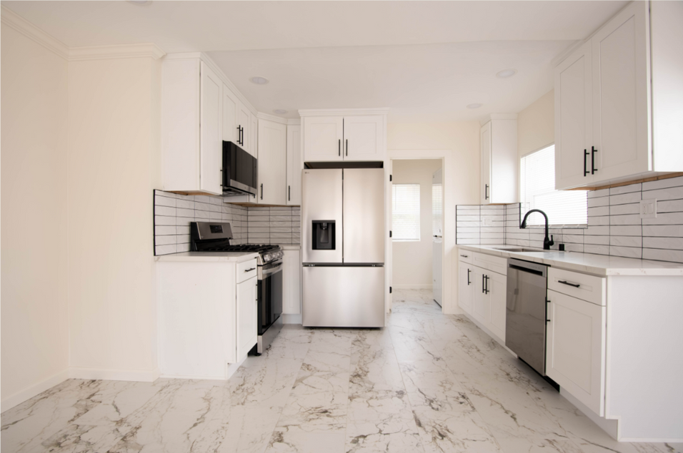 Bright modern kitchen with white cabinets, stainless appliances, marble floor, and black tile backsplash