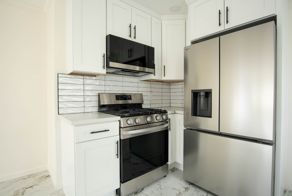 Modern white kitchen with stainless steel appliances and black accents