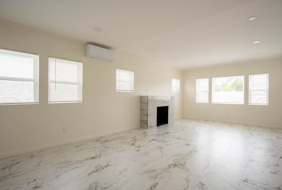 Empty white living room with marble floor, fireplace, and large windows