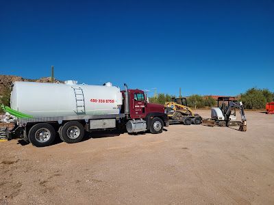 A red and white semi truck is parked in a dirt lot.