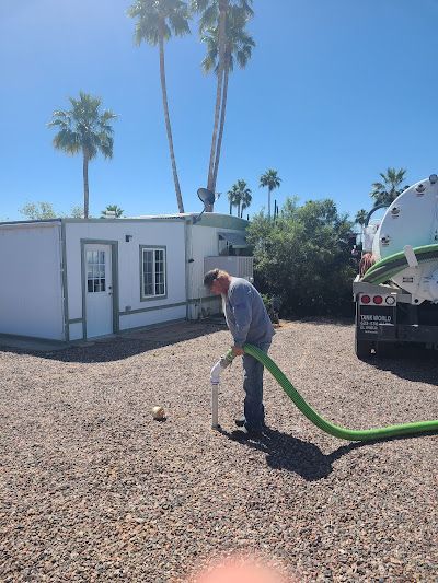 A man is pumping water from a hose into a septic tank.