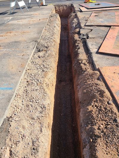 A trench is being dug in the dirt on the side of the road.