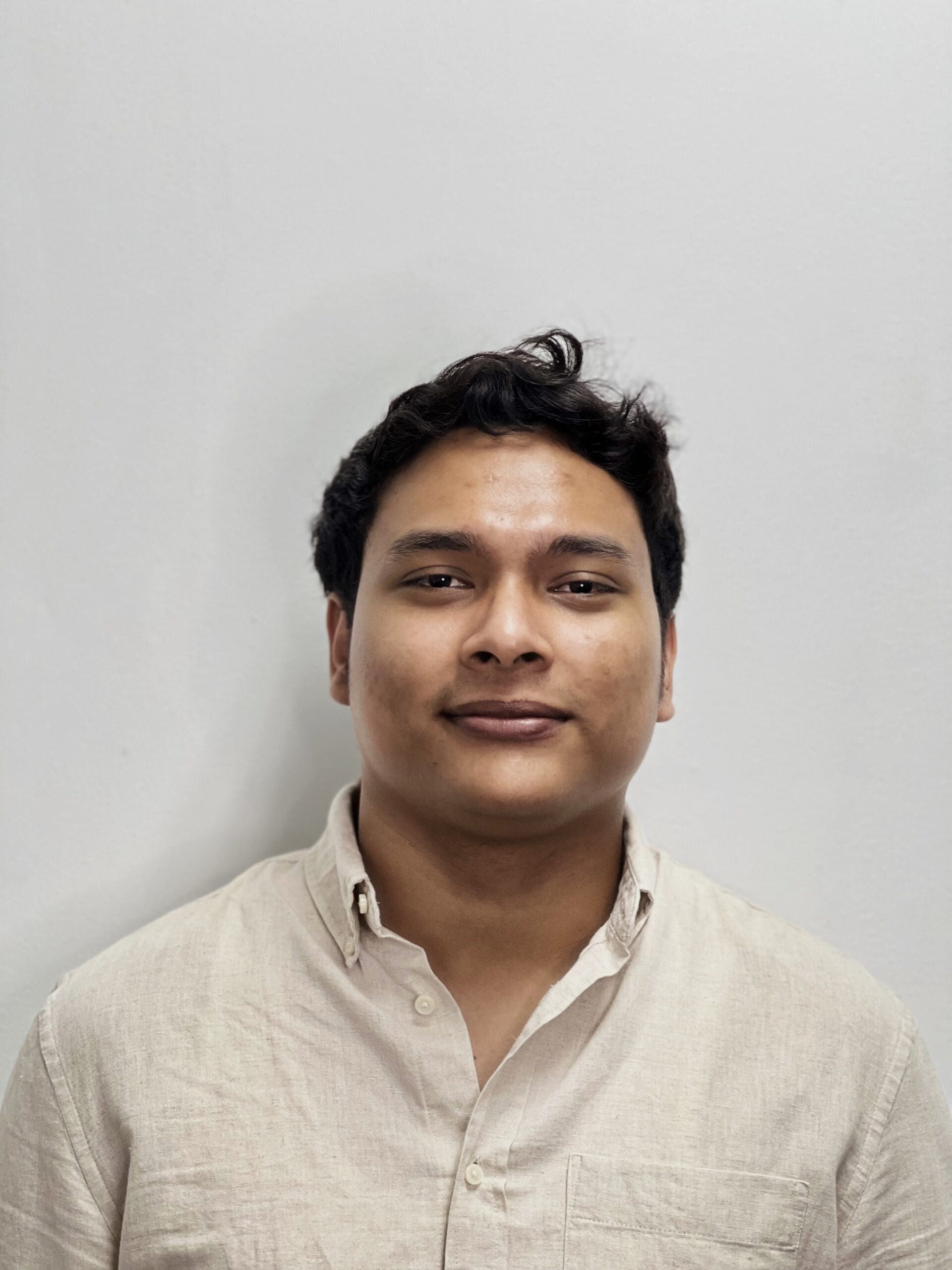 Person in a light beige shirt smiling against a plain gray background