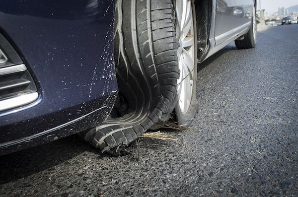 A car with a flat tire on the side of the road. | Lex Brodies 