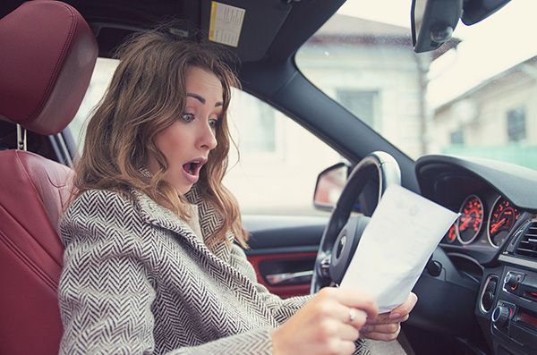 A woman is sitting in a car reading a piece of paper. | Lex Brodies 