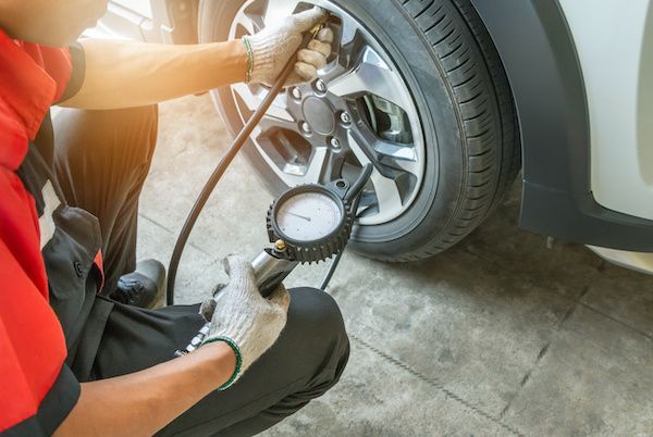 A man is checking the tire pressure of a car. | Lex Brodies 