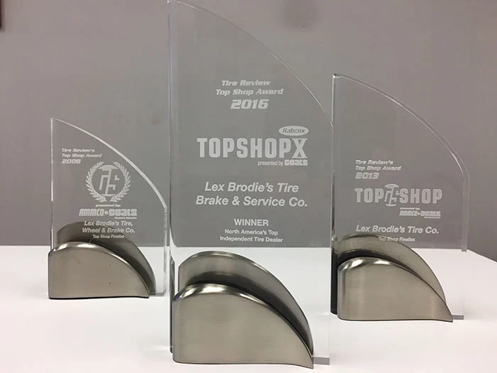 Three trophies are sitting on a table and one of them says topshopx | Lex Brodies