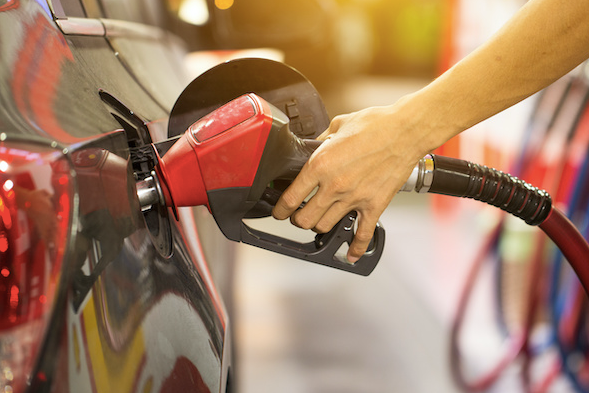 A person is pumping gas into a car at a gas station. | Lex Brodies 