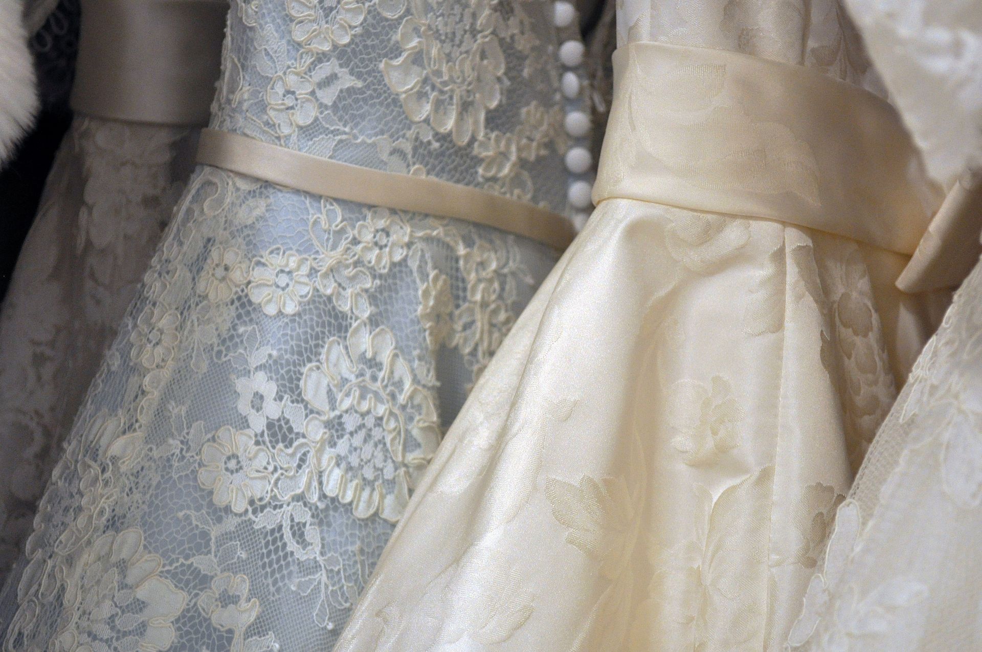 A row of wedding dresses are hanging in a closet.