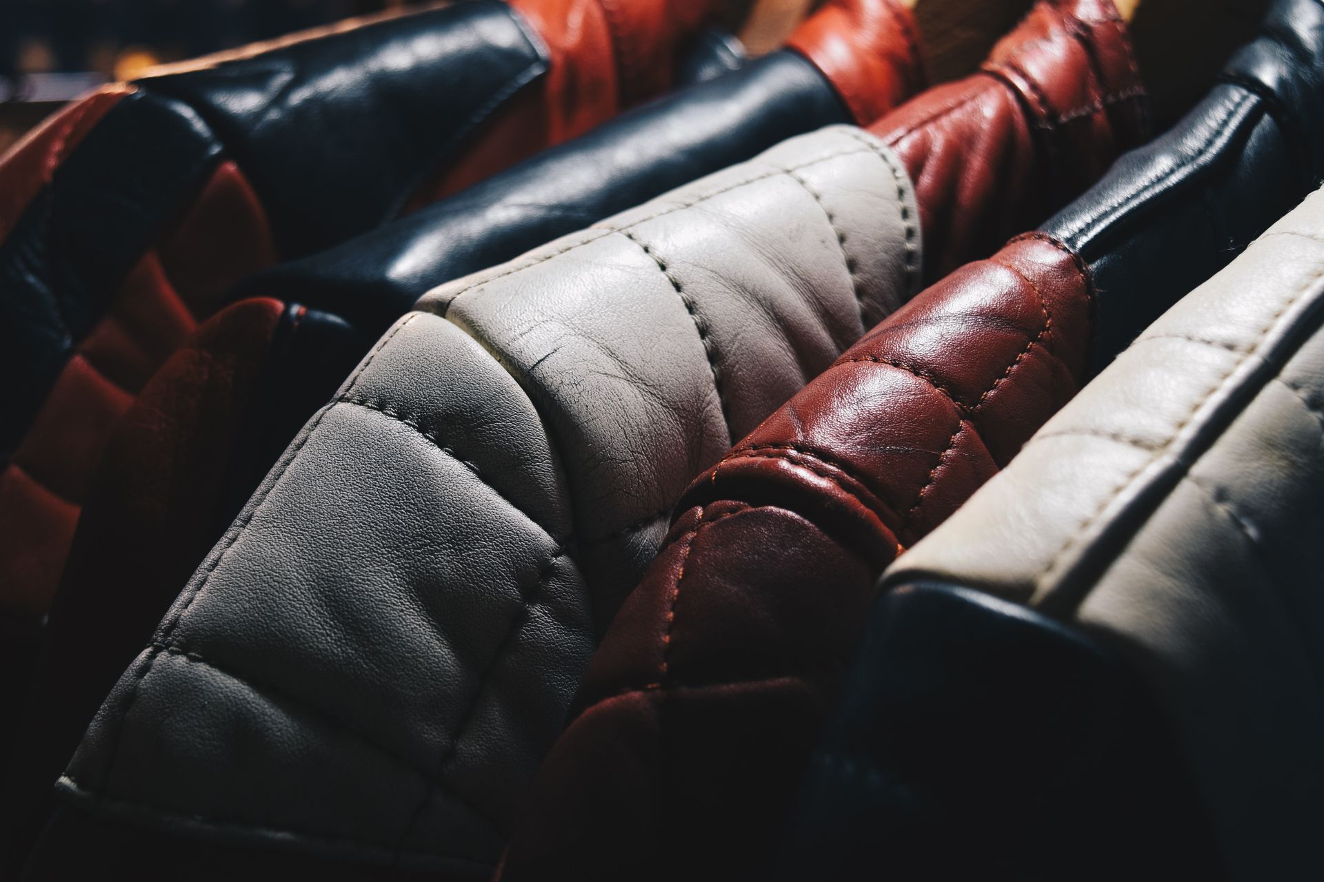 A close up of a row of leather jackets hanging on a rack.