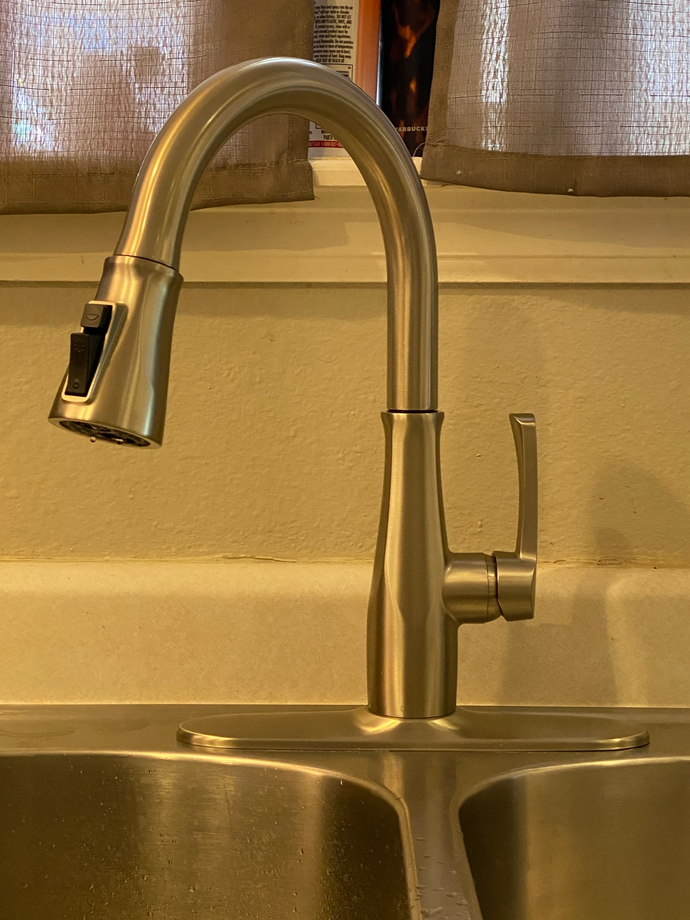 Kitchen sink with a stainless steel pull-down faucet and beige countertop backsplash.