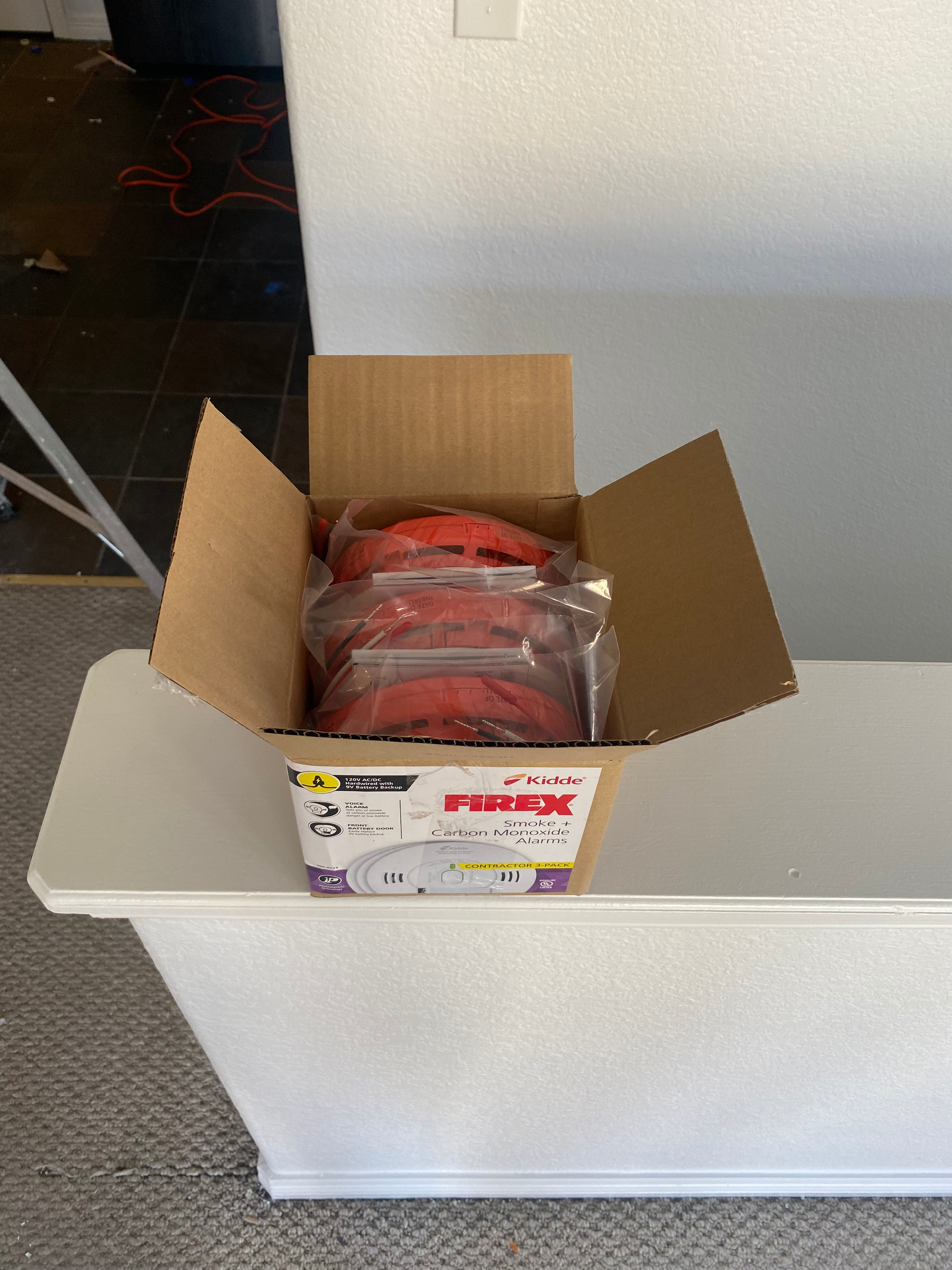 Open cardboard box on a white surface, filled with red packaged items indoors.