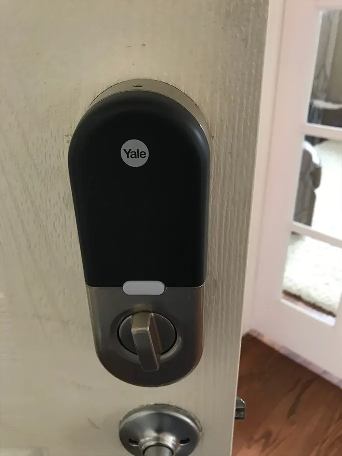 Black Yale smart lock on a white door with a silver deadbolt beneath it.