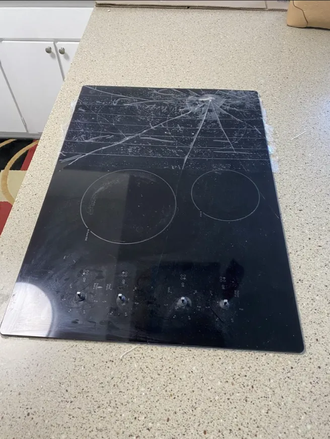 Scratched black glass cooktop on a beige kitchen countertop