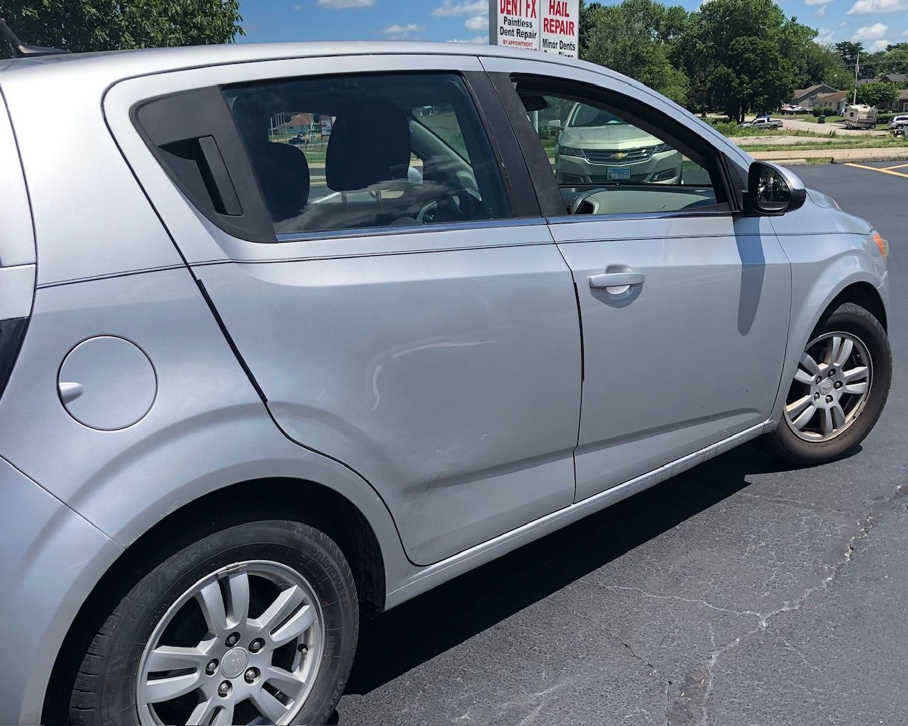 Silver hatchback car parked on a street in bright sunlight, side view