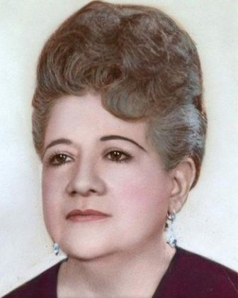 Woman with wavy, bouffant hairstyle, wearing earrings, looking toward viewer.