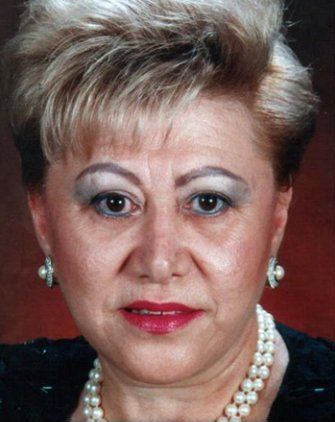 Woman wearing pearl necklace and earrings, looking at the camera.