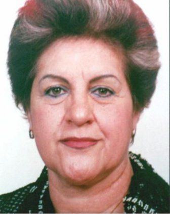 Woman with short, styled hair, wearing earrings and a dark blazer; looking directly at the viewer.