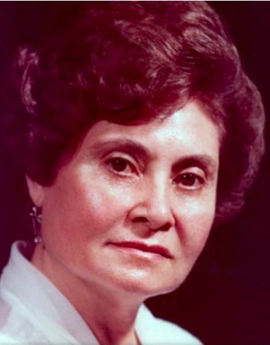 Portrait of a woman with dark hair, wearing a white shirt, looking forward with a neutral expression.