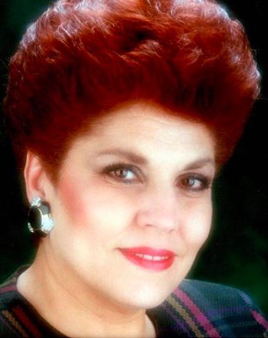 Woman with red hair, wearing earrings and lipstick. Smiling, facing the camera.