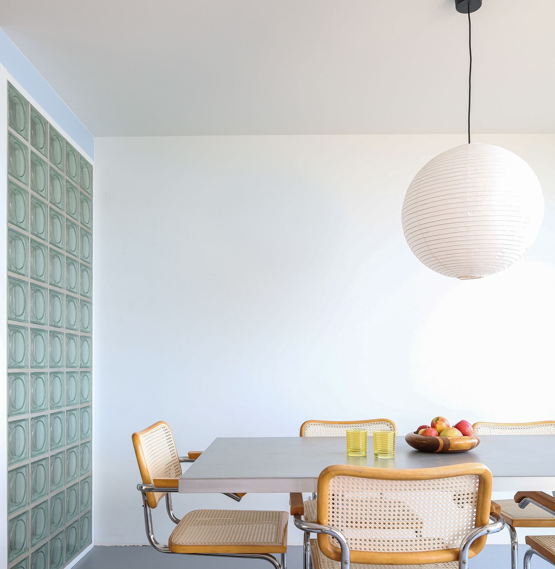 Eetkamer met tafel, stoelen, glazen bouwstenenwand en hanglamp. Glass blocks. Glazen blokken.