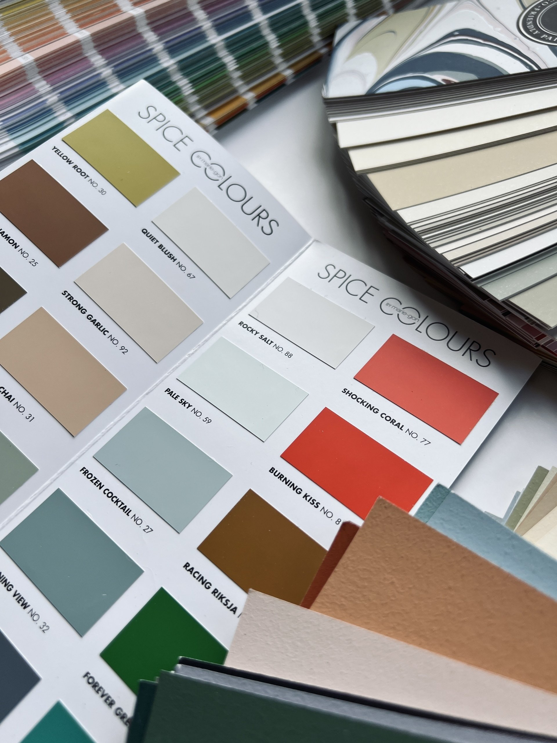 Verfstalen en stofstalen in diverse kleuren, waaronder groen, blauw, bruin en oranje, voor interieurontwerp. Kleuradvies