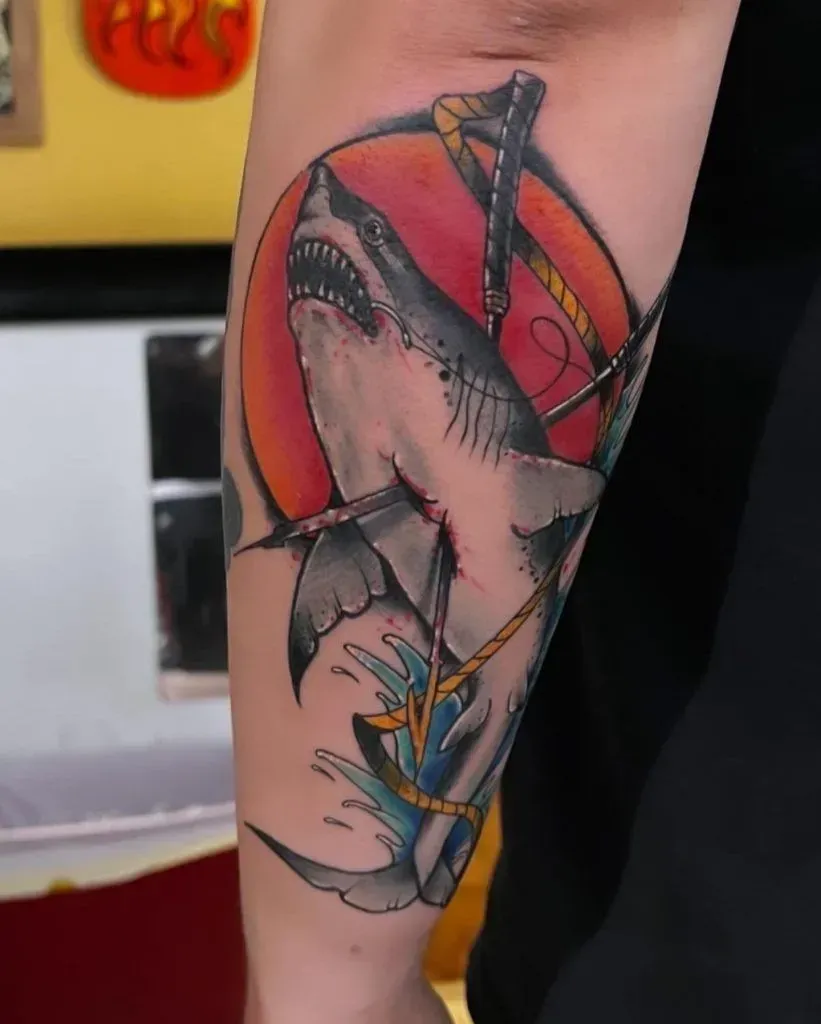 Tattoo of a great white shark biting a musical instrument with a red sun background.