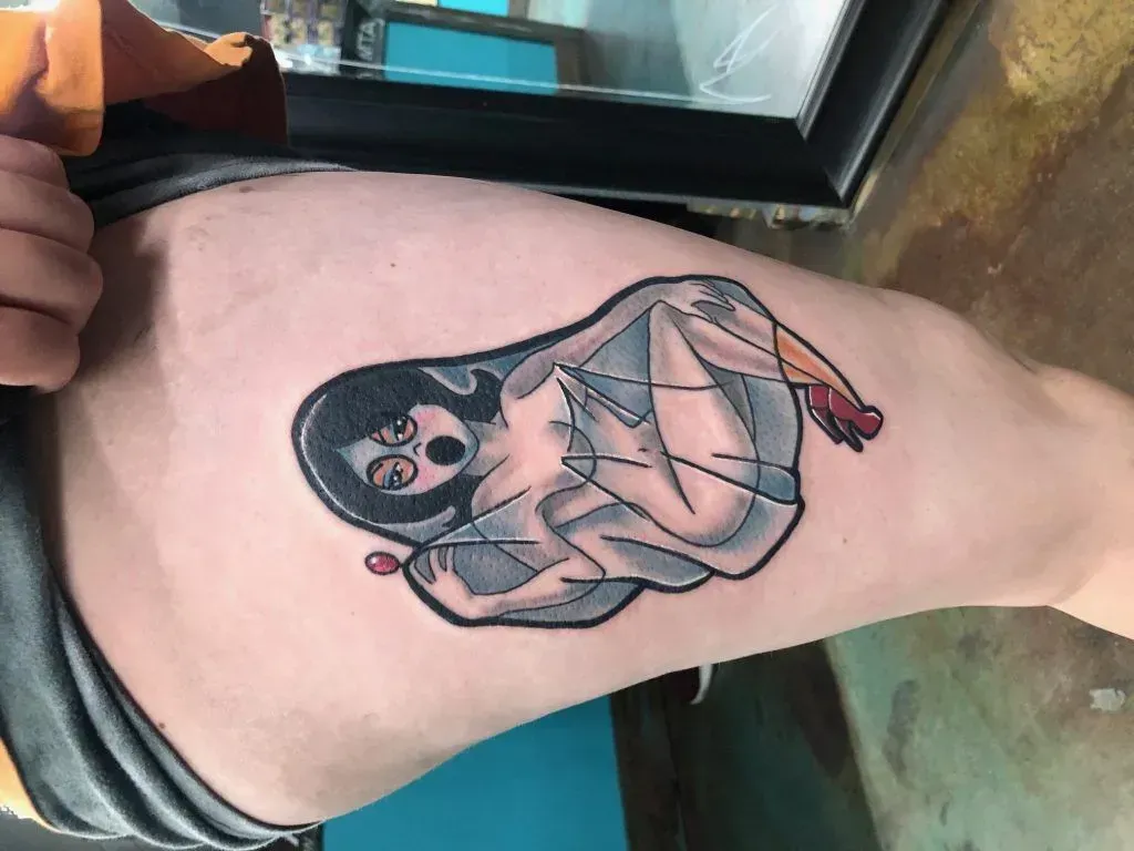 Ghost tattoo on thigh, gray sheet, black hair, red hand, open mouth.
