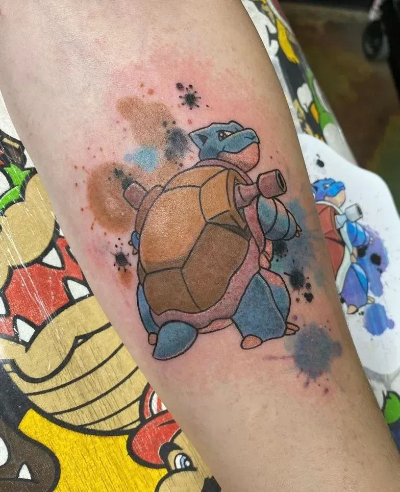Tattoo of Blastoise, a blue Pokémon, with watercolor effect on forearm.
