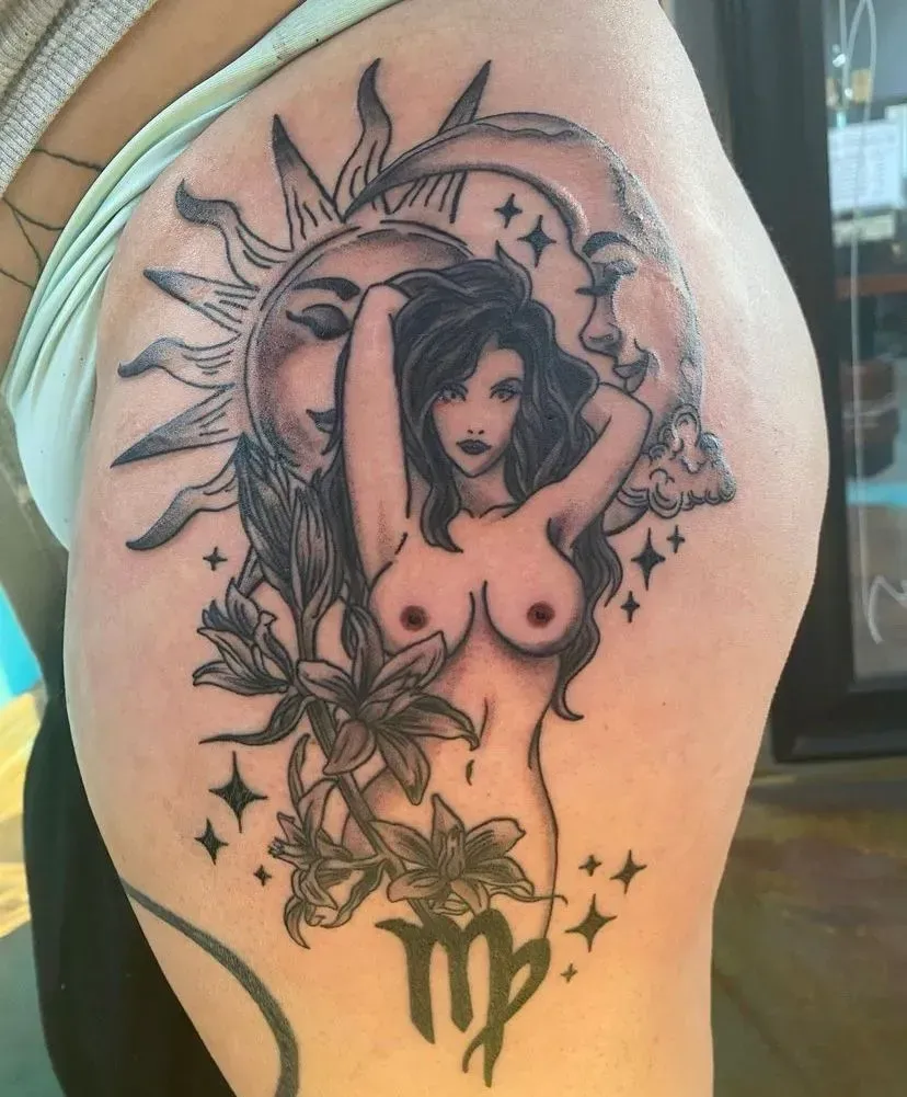 Tattoo of nude woman, sun, moon, flowers, and Virgo symbol. Black and gray ink on skin.