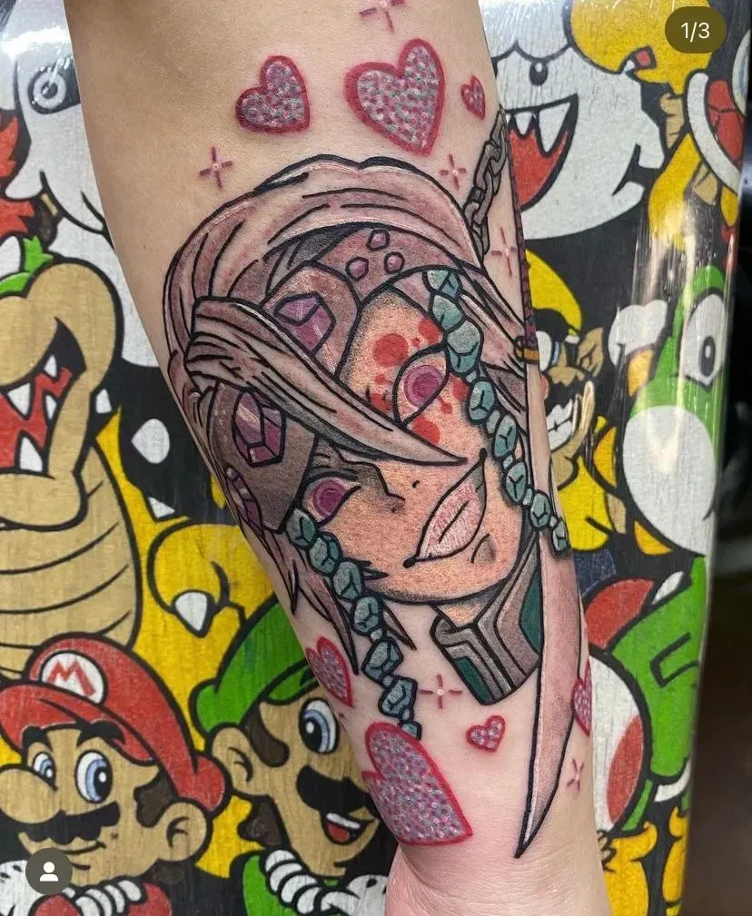 Tattoo of a stylized character with hearts and jewels on an arm. Background features Mario characters.