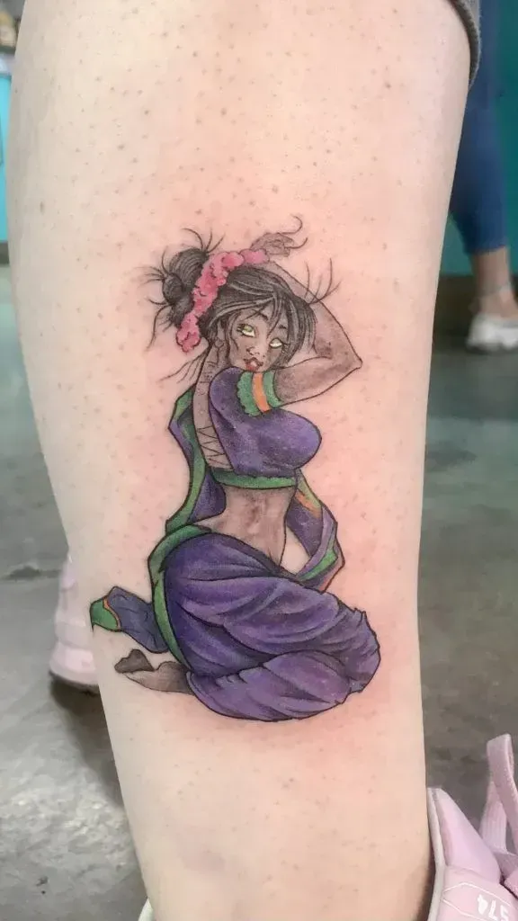 Tattoo on leg: woman in purple outfit, arms above head, kneeling. Pink bow, gray skin.