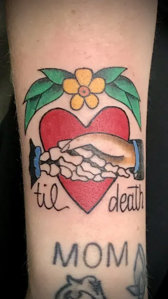 Tattoo: Heart with clasped skeletal hand and flesh hand. 