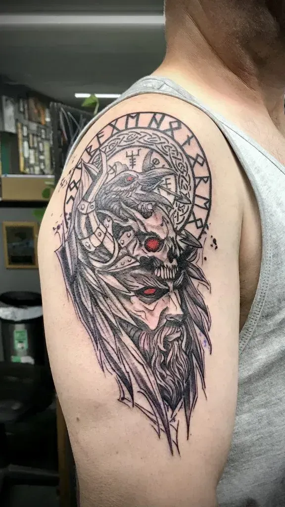 Tattoo of a horned figure with runes, red eyes, and a long beard, on a man's upper arm.
